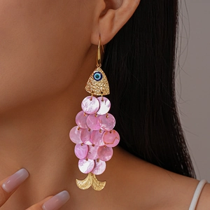 Macro view of gold fish earring with pink shell scales and devil eye detail