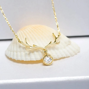 Macro shot of 18K gold plated elk antler pendant with sparkling cubic zirconia on a shell