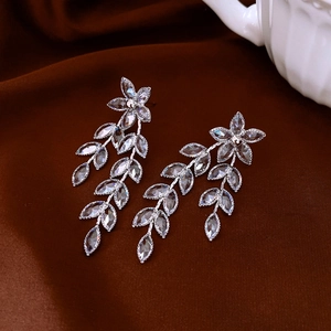 Detailed close-up of silver floral earrings with crystal leaf tassels on velvet backdrop