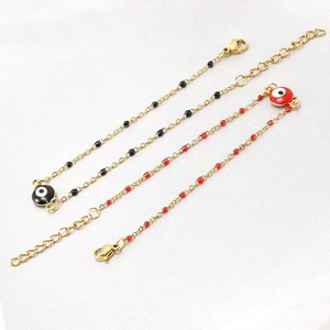 Detail of red and black evil eye charms on adjustable gold-plated stainless steel chains