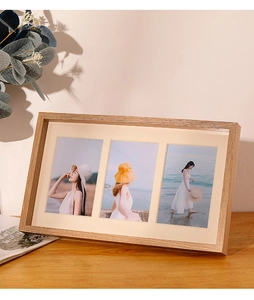 Detailed view of triple-frame wooden photo display with beige matting on a wooden desk