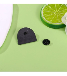 Detail showing a semi-circle black enamel pin back with a rubber clutch on a green surface