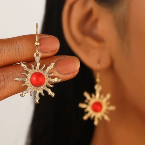 Bohemian vintage sun-shaped gold earrings with red crystal center stone shown on a model