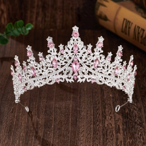 Close-up of bridal crown featuring pink crystals and rhinestones on dark wood