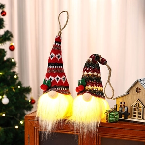 Leuchtende Weihnachtsgnome mit Strickmützen und warmen LED-Bärten auf einem Holztisch dekoriert