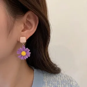 Elegant purple daisy earrings with yellow centers and beige square studs on model