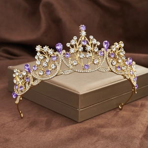 Detail of golden baroque crown with purple and clear rhinestones on leaf metal base