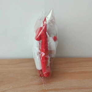 Détail du sac cadeau de Noël en tricot rouge et blanc dans son emballage transparent de protection