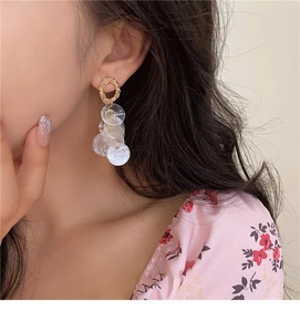 Close-up of golden textured hoop earrings with dangling translucent shell sequins