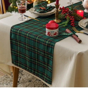 Close-up of green plaid table runner with festive pine cones and Christmas decor