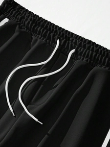 Detailed macro view of black joggers featuring an elastic waistband with white drawstrings