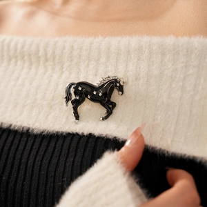Detail of vintage enamel horse brooch with sparkling rhinestones on white sweater