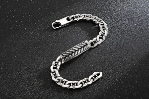 Macro shot of silver wheat chain bracelet with carved cross links on black background