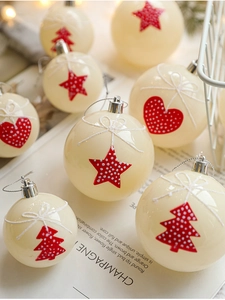 Close-up of cream Christmas baubles with red star patterns and festive glitter ribbons