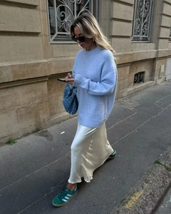 Détail d'une jupe longue en satin blanc avec un pull en maille bleu clair et un sac à main