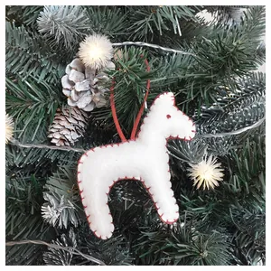 Close-up of white felt horse ornament with red stitching on a decorated Christmas tree