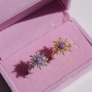 Detail of sunflower opal rings in gold and silver finish placed in a pink velvet box