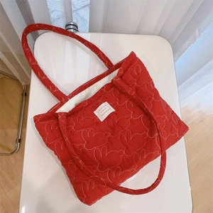 Close-up of red quilted tote bag featuring white rabbit embroidery and woven label