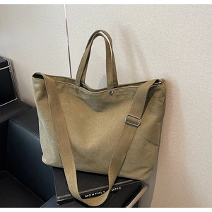 Olive green large canvas tote bag with adjustable shoulder strap in home setting
