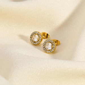 Detailed close-up of golden round emerald-cut cubic zirconia studs on beige silk fabric