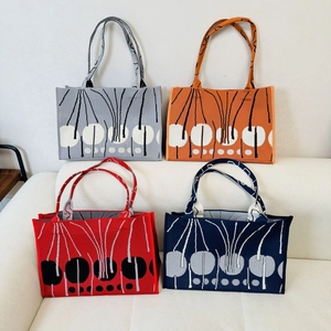 Collection of knitted tote bags with abstract floral patterns in grey, orange, red, and blue