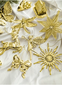 Detailed close-up of golden Christmas ornaments including elk and snowflakes on white silk