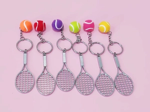 Detailed view of six colorful mini tennis ball and racket keychains on pink background