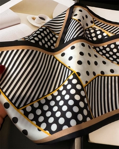 Detail of elegant polka dot and stripe printed silk scarf held by hand with soft drape