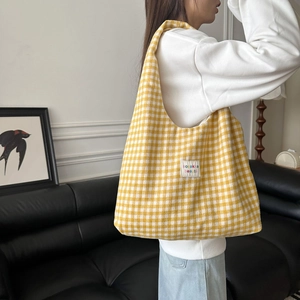 Detail einer gelb-weiß karierten Stricktasche mit Markenlabel auf der Schulter