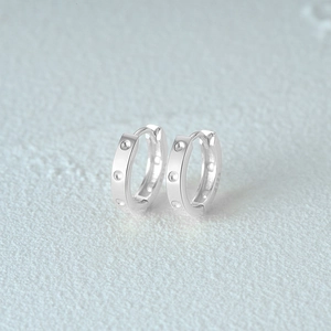 Macro detail of 925 sterling silver hoop earrings with triple inlaid diamond accents