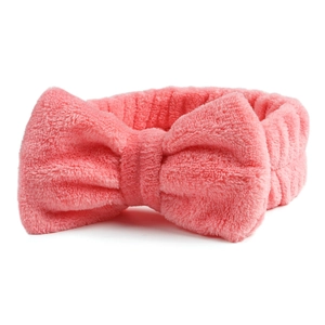 Detailopname van de roze koraalvlies hoofdband met zachte strik voor gezichtsreiniging