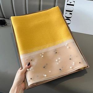 Detail of yellow silk scarf with sheer beige fabric and elegant pearl embellishments