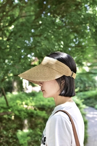 Detail of wide brim raffia sun hat with adjustable buckle on outdoor forest background