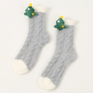 Detail von grau-weißen Korallenvlies-Socken mit dekorativem 3D-Plüsch-Weihnachtsbaum
