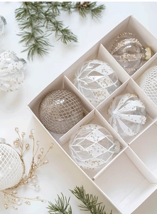 Détail de boules de Noël de 8cm avec motifs pailletés or et blanc dans une boîte cadeau