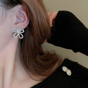 Detailed close-up of sparkling flower earrings and pearl brooch set on model