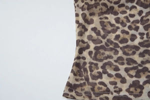 Detailed close-up of brown leopard print mesh fabric with breathable texture and sewing hem