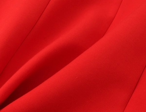 Detailed macro view of the premium red elastic fabric texture on a bow mini dress