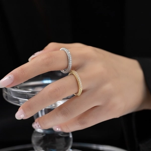 Detail shot of gold and silver full-diamond stacked rings on hand over black background