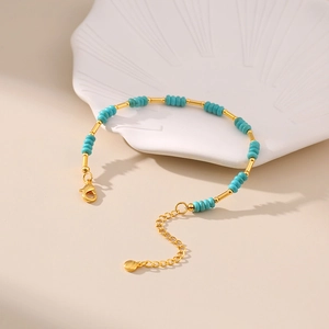 Detail of turquoise beaded bracelet with gold-plated tubes and adjustable clasp on shell