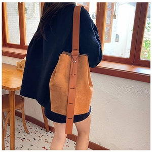 Suede bucket bag in camel brown with wide shoulder strap shown on a model