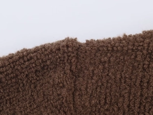 Macro shot of brown textured bouclé fabric showing the curly fiber texture of the bomber jacket