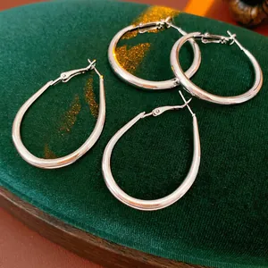 Minimalist silver geometric U-shaped hoop earrings on dark green velvet background