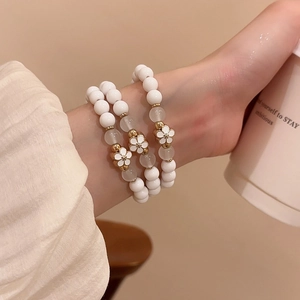 Three-piece acrylic beaded bracelet set with white oil-dripped flowers worn on a wrist