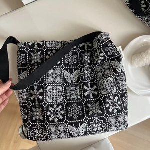Close-up of black canvas bag featuring white butterfly embroidery and simple wish label