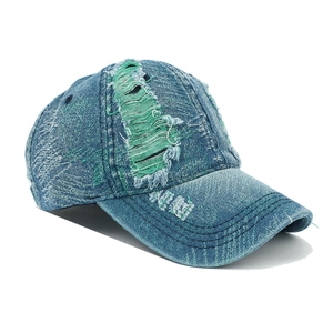 Detail view of vintage blue denim baseball cap with green distressed ripped holes