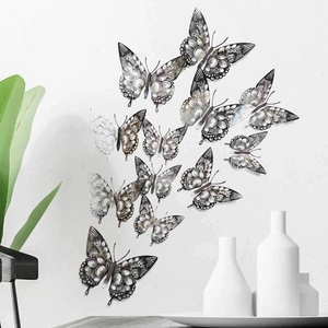 Detailed view of 12 black 3D hollow butterfly wall decals on a gray wall surface