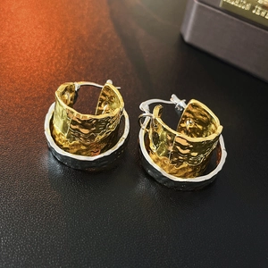 Detail of two-tone hammered metal earrings in gold and silver with 925 silver hallmark