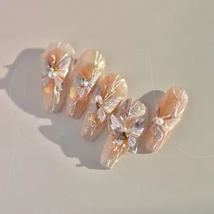 Detail of pink press-on nails with iridescent 3D butterflies and pearl accents