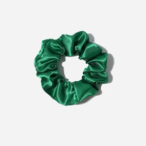 Macro detail of dark green satin scrunchie showing glossy silk texture and pleated design